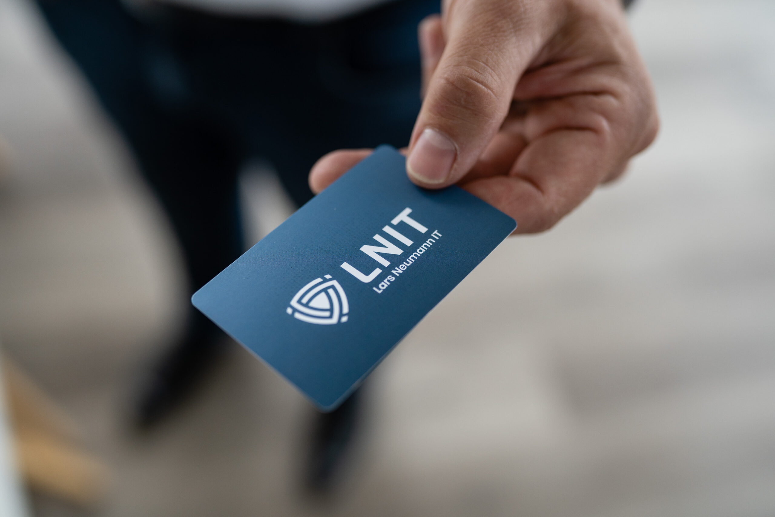 Lars Neumann hält eine Visitenkarte mit Kontakt Daten bereit